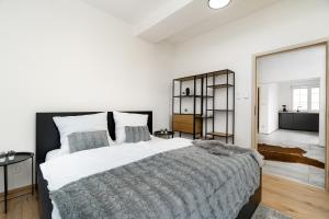 a white bedroom with a large bed and a mirror at Beautiful Apartments With Parking In a Quiet Location in Ostrava