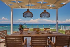 una sala da pranzo con tavolo e vista sull'oceano di Ducato di Zante Luxury Beach Villa a Kypseli
