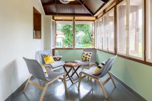 a room with chairs and a table and windows at Villa Aangan by StayVista - A heritage charm with Swimming pool, Gazebo, Projector room & Indoor games in Lonavala