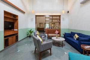 a living room with a blue couch and a table at Villa Aangan by StayVista - A heritage charm with Swimming pool, Gazebo, Projector room & Indoor games in Lonavala