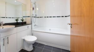 La salle de bains est pourvue d'une baignoire blanche, de toilettes et d'un lavabo. dans l'établissement The Spires Serviced Apartments Birmingham, à Birmingham