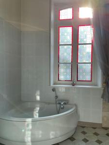 een witte badkamer met een bad en een raam bij Le Jardin du Clocheton, jardin et parkings privés, centre Etretat in Étretat