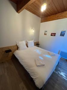 1 dormitorio con 1 cama con sábanas blancas y suelo de madera en Barcelonnette location avec jardin, en Barcelonnette