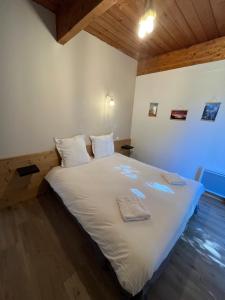 sypialnia z łóżkiem z białymi prześcieradłami i drewnianą podłogą w obiekcie Barcelonnette location avec jardin w mieście Barcelonnette