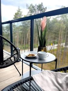 a table with a cup of coffee and a flower on a porch at Rogowo 117J Shellter Apartments in Rogowo