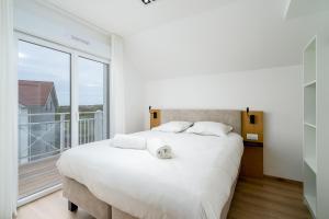 - une chambre avec un grand lit blanc et une grande fenêtre dans l'établissement Evancy Equihen-Plage, à Équihen-Plage