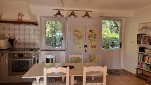 een keuken met een tafel en stoelen en 2 ramen bij La Cassine, gîte des Lucioles en Provence in Montségur-sur-Lauzon