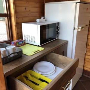a kitchen with a microwave and a shelf with plates at Zajazd Private in Suwałki