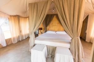 a bedroom with a canopy bed with two chairs at Le Lenze Don Mimì Glamping in Mattinata
