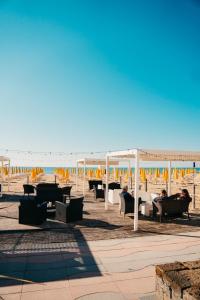 einen Strand mit Tischen, Stühlen und Sonnenschirmen in der Unterkunft Hotel Villa Sorriso in Lido di Jesolo