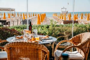 un tavolo con cibo e una bottiglia di vino in spiaggia di Hotel Villa Sorriso a Lido di Jesolo