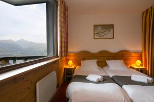 Duas camas num quarto com uma janela grande em VVF La Plagne Montalbert Paradiski em Aime La Plagne