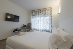 a white bedroom with a white bed and a window at Supernova in Savona