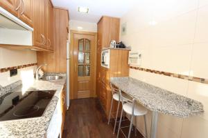 una cocina con encimeras de granito y armarios de madera en Apartamento BELLAS VISTAS, en Béjar