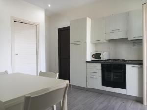 帕爾蓋利亞的住宿－Appartamenti Tropea Gargano，厨房配有白色橱柜和带微波炉的桌子。