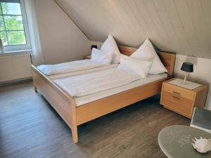 Bett mit weißen Kissen auf einem Zimmer in der Unterkunft Pension Lotsenhaus in Greetsiel