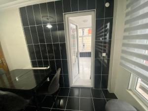 a black tiled bathroom with a mirror and a chair at Homes4 in Pelitli