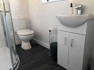 a white bathroom with a toilet and a sink at Ash Cottage in Skegness