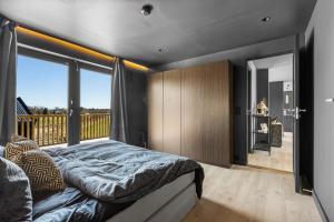 a bedroom with a large bed and a balcony at Nytt og sjønært hus med boblebad til leie! in Grimstad