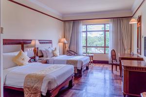 um quarto de hotel com duas camas e uma secretária em Sokha Angkor Resort em Siem Reap