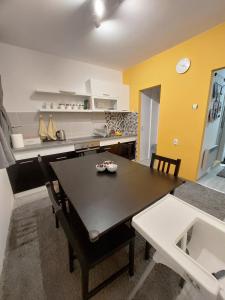 een keuken met een zwarte tafel en een gele muur bij Apartman Pletisanak in Gornji Milanovac