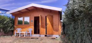 een kleine houten hut met 2 stoelen en een veranda bij Domki letniskowe nad morzem in Pogorzelica