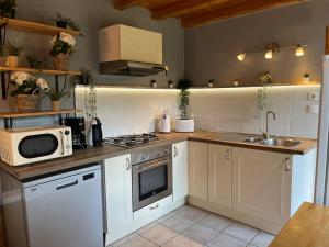 a kitchen with white cabinets and a sink and a microwave at La maison des commis in Morestel