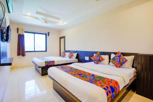 a hotel room with two beds and a window at FabExpress Vivaanta Palace in Shirdi