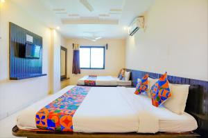 a hotel room with two beds and a television at FabExpress Vivaanta Palace in Shirdi