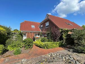 une maison en briques avec un toit rouge et un jardin dans l'établissement Pension Lotsenhaus, à Greetsiel