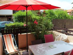 een tafel en stoelen met een rode parasol bij Appartement Port-la-Nouvelle, 3 pièces, 4 personnes - FR-1-229C-74 in Port-la-Nouvelle