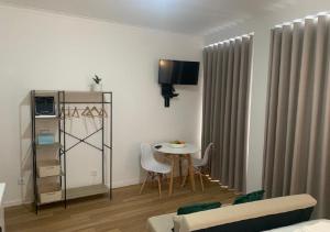 uma sala de estar com uma mesa e cadeiras e uma televisão em GuimaraesLiving - Hostel & Adventure em Guimarães