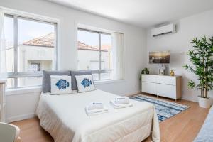 um quarto branco com uma cama grande e janelas em Comfy Sunny Flat - Prime Location em Porto