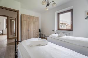 biały pokój z 2 łóżkami i oknem w obiekcie Casa Stefano w mieście Riva del Garda