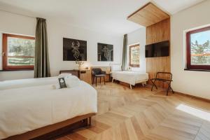 um quarto de hotel com duas camas e uma secretária em B&B Hotel Passo Tre Croci Cortina em Cortina dʼAmpezzo