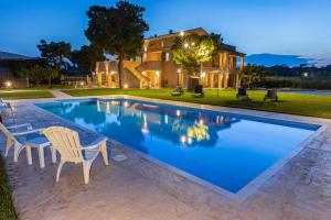 a swimming pool with chairs and a house in the background at Casale Ferrantino in Giulianova