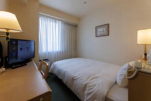 a hotel room with a bed and a desk with a phone at Shimonoseki Station West Washington Hotel Plaza in Shimonoseki