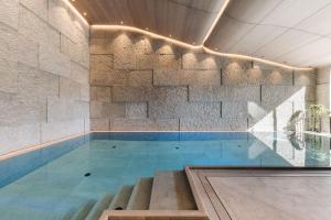 a swimming pool with a stone wall at LE CHALET - Luxury Hideaway in Oberlech