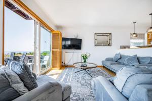 a living room with two couches and a tv at Pebble Paradise Beachfront Family Getaway in Pevensey