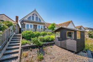 a house with a small shed in the yard at Pebble Paradise Beachfront Family Getaway in Pevensey
