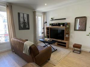 een woonkamer met een bank en een televisie bij Le Paris Appart' T2 au centre du Mans in Le Mans +20 foto's