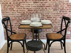 een tafel met twee stoelen en een bakstenen muur bij Le Paris Appart' T2 au centre du Mans in Le Mans