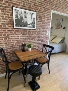 een tafel en stoelen in een kamer met een bakstenen muur bij Le Paris Appart' T2 au centre du Mans in Le Mans