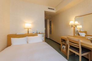 a hotel room with a bed and a desk and a mirror at Shimonoseki Station West Washington Hotel Plaza in Shimonoseki