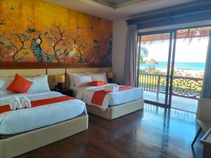 two beds in a room with a view of the ocean at Costa Celine Beach Resort in Kinablañgan