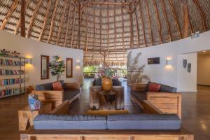 een woonkamer met banken en een groot rieten dak bij Morena Resort in Willemstad