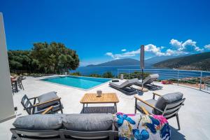 a patio with a table and chairs and a swimming pool at Villa Fortuna in Ayia Evfimia