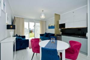 a kitchen and living room with a white table and pink chairs at Pokoje Gościnne IDALIA - Blisko Plaży Komfort i Wygoda in Karwia