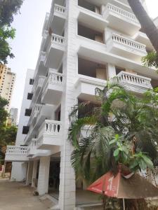 ムンバイにあるWhite House by Maxxvalue Service Apartments Bandraのヤシの木が目の前に広がる白い建物