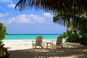 two chairs and a table on a beach at Les Villas D'or in Baie Sainte Anne